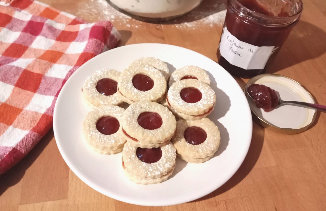 Des petits biscuits sablés rond à la confiture de fraise dans une assiette