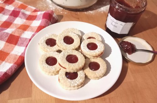 Des petits biscuits sablés rond à la confiture de fraise dans une assiette