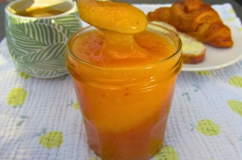 Pot de confiture de pêche de vigne maison avec une cuillère, servi avec un croissant et un café